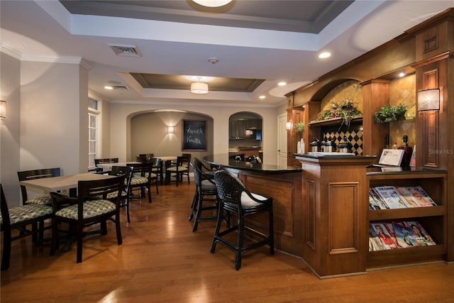 513 Mirasol Cir Unit 101, Celebration, FL 34747 - community bar area featuring a raised ceiling, arched walkways, ornamental molding, and light wood-style floors