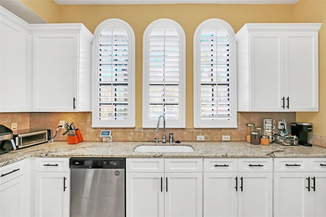 kitchen featuring stainless steel dishwasher, white cabinets, and sink