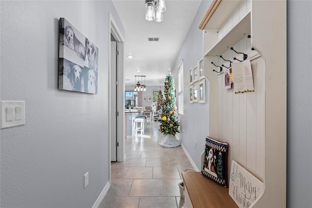 hallway featuring light tile patterned flooring and a chandelier