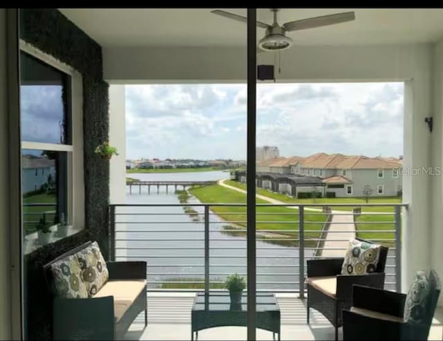 balcony with ceiling fan and a water view