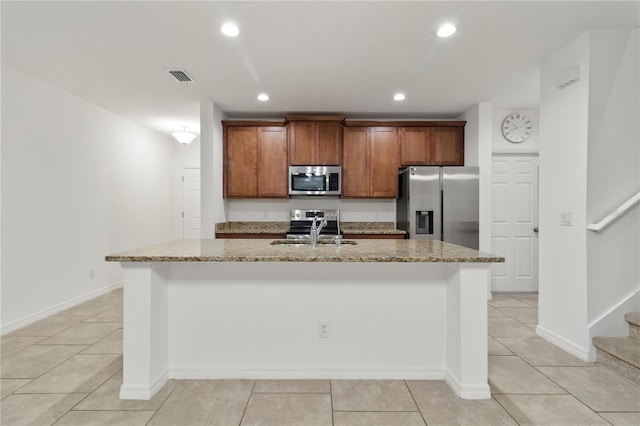 kitchen featuring light stone countertops, appliances with stainless steel finishes, sink, and an island with sink