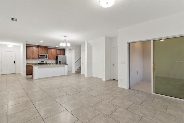 kitchen featuring pendant lighting, a center island, light tile patterned floors, stainless steel appliances, and a chandelier