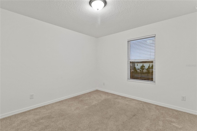 empty room featuring a textured ceiling and light colored carpet