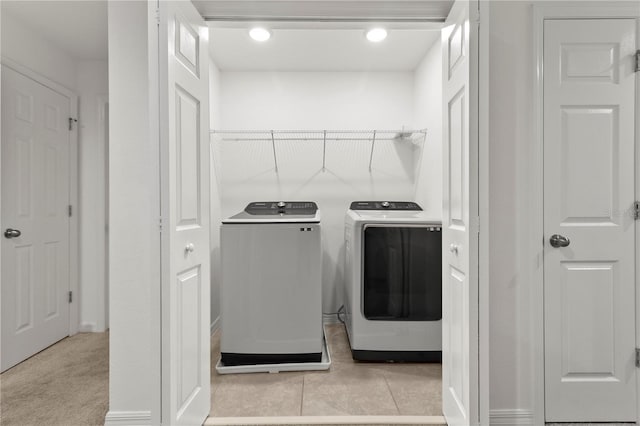 clothes washing area with light carpet and washing machine and clothes dryer