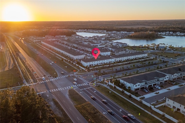 aerial view at dusk featuring a water view