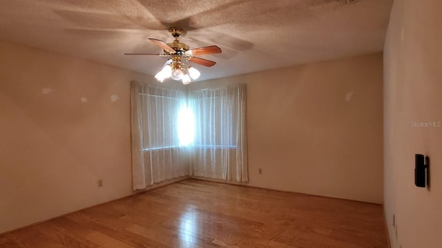 empty room with ceiling fan, light hardwood / wood-style floors, and a textured ceiling