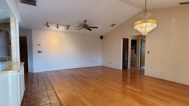 interior space with ceiling fan with notable chandelier, light hardwood / wood-style flooring, and vaulted ceiling