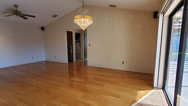 empty room featuring ceiling fan with notable chandelier, light hardwood / wood-style floors, and vaulted ceiling