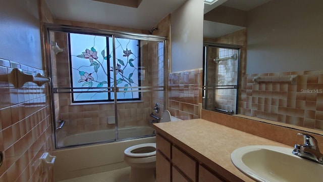 full bathroom with vanity, toilet, enclosed tub / shower combo, and tile walls