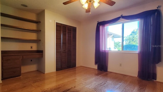 unfurnished bedroom featuring a textured ceiling, a closet, light hardwood / wood-style flooring, and ceiling fan