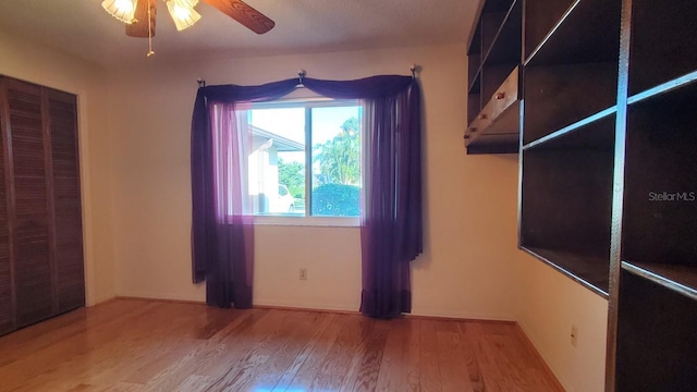 unfurnished bedroom featuring hardwood / wood-style floors, a closet, and ceiling fan