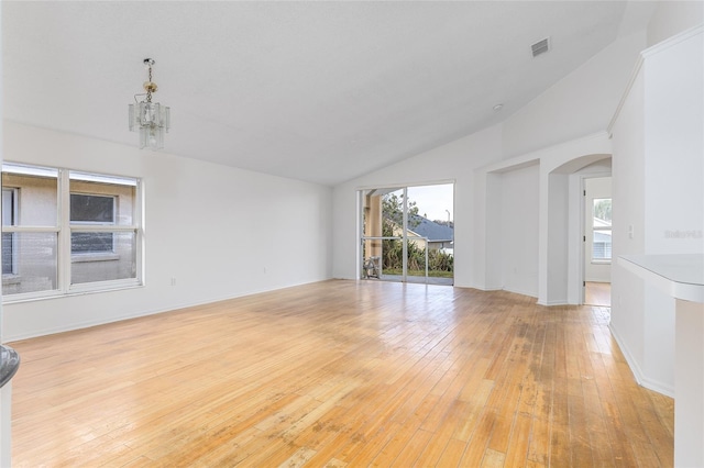 unfurnished room featuring lofted ceiling, a chandelier, and light hardwood / wood-style flooring