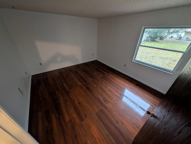 spare room with dark hardwood / wood-style flooring and a textured ceiling