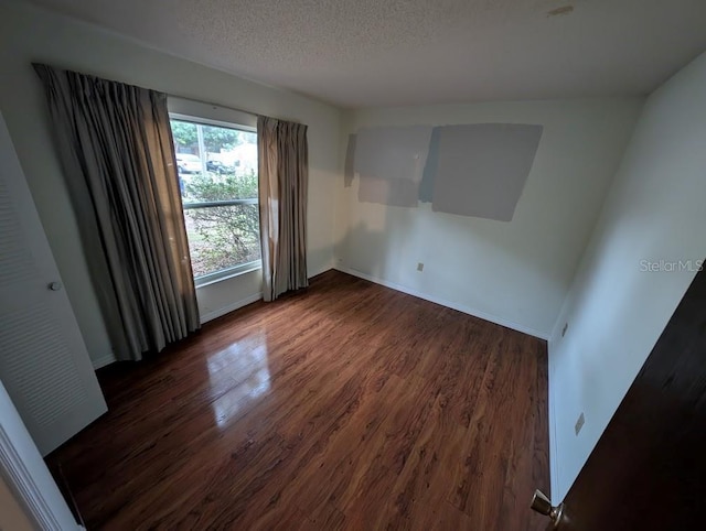 empty room featuring a textured ceiling and dark wood-type flooring