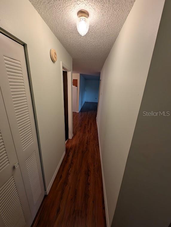 corridor featuring dark wood-type flooring and a textured ceiling