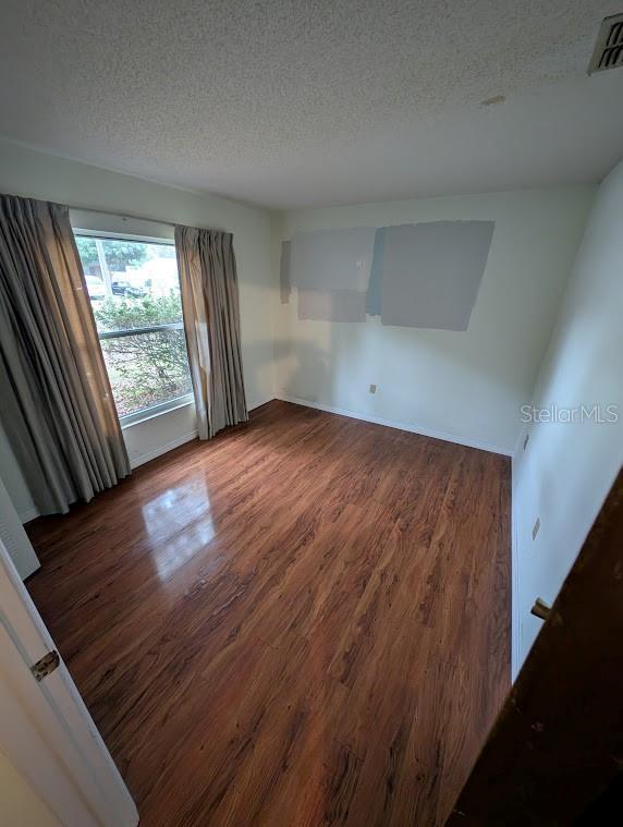 empty room with a textured ceiling and dark hardwood / wood-style floors