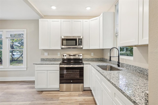 kitchen with a healthy amount of sunlight, white cabinetry, sink, and appliances with stainless steel finishes