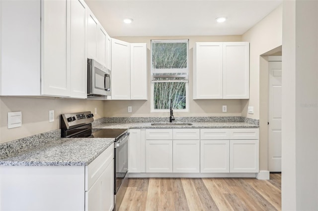 kitchen with white cabinets, light wood-type flooring, stainless steel appliances, and sink