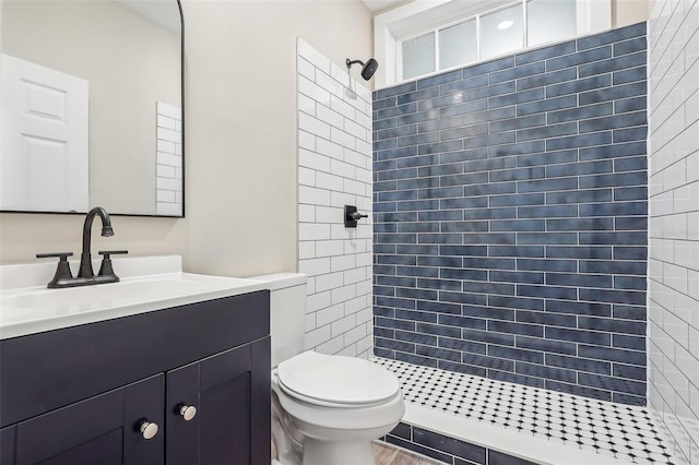 bathroom featuring tiled shower, vanity, and toilet