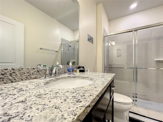 bathroom with an enclosed shower, vanity, and toilet