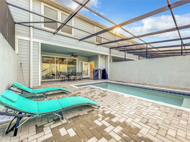 view of swimming pool featuring glass enclosure, ceiling fan, and a patio