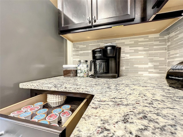 details with kitchen peninsula, dark brown cabinetry, tasteful backsplash, and light stone counters