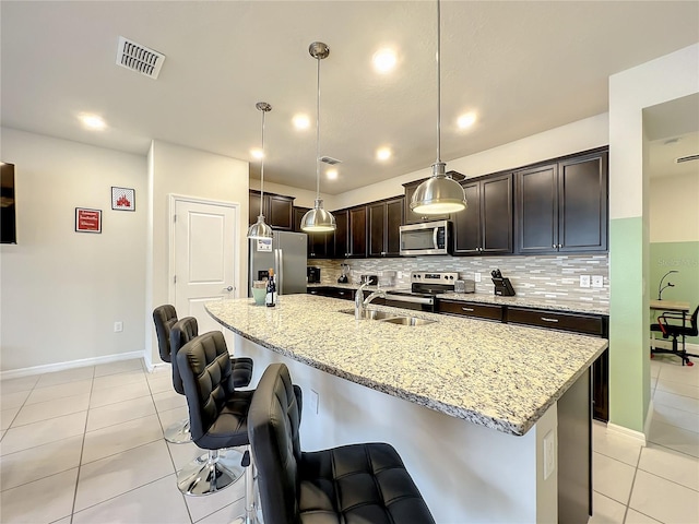 826 Paradise Dr, Davenport, FL 33897 - kitchen featuring stainless steel appliances, light tile patterned floors, a breakfast bar area, backsplash, and dark brown cabinetry