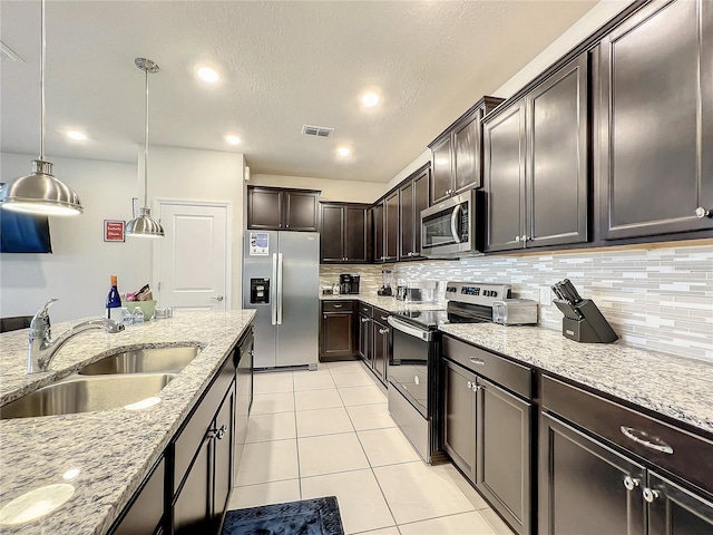 kitchen with sink, pendant lighting, dark brown cabinets, light tile patterned floors, and appliances with stainless steel finishes