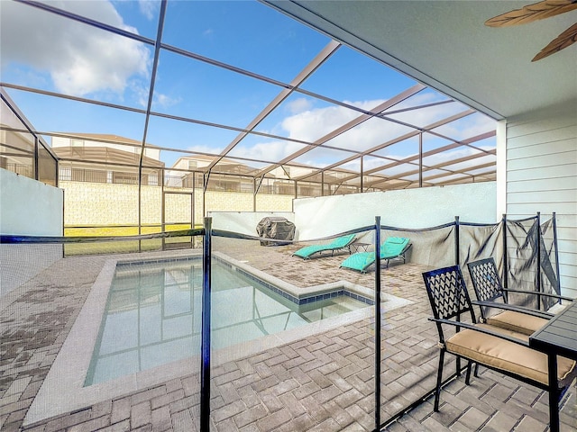 view of swimming pool featuring glass enclosure, ceiling fan, and a patio