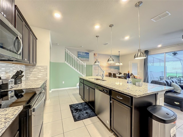 kitchen featuring pendant lighting, sink, an island with sink, dark brown cabinetry, and stainless steel appliances