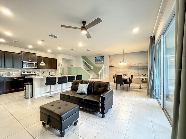 living room with ceiling fan with notable chandelier and light tile patterned floors