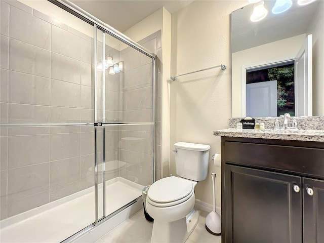 bathroom with tile patterned floors, vanity, a shower with shower door, and toilet