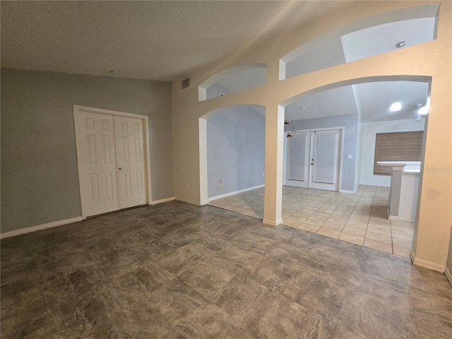 tiled spare room featuring lofted ceiling