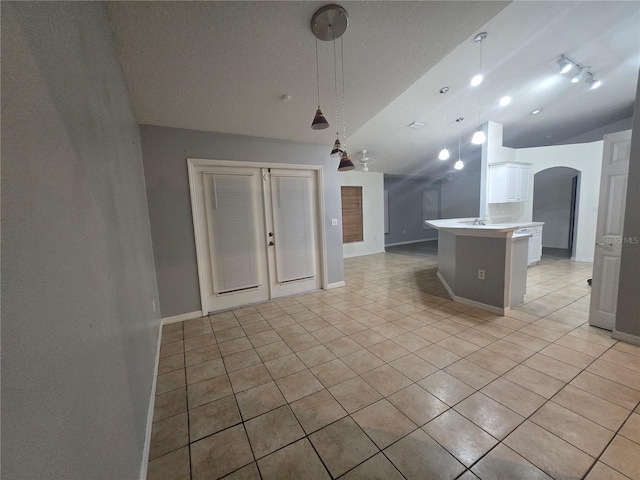 kitchen with a textured ceiling, a center island, vaulted ceiling, light tile patterned floors, and hanging light fixtures