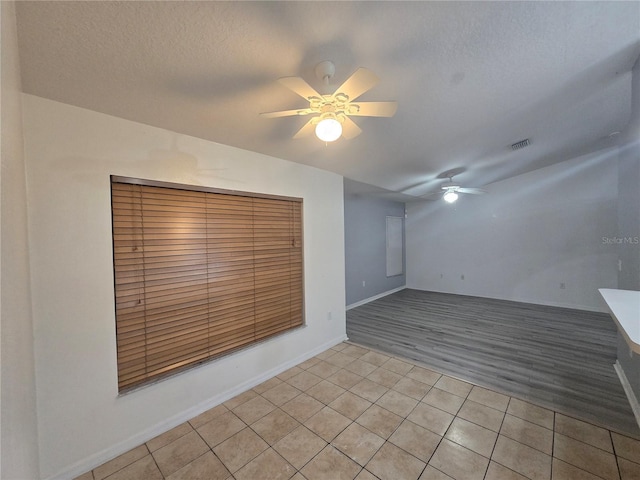 tiled spare room with a textured ceiling and ceiling fan