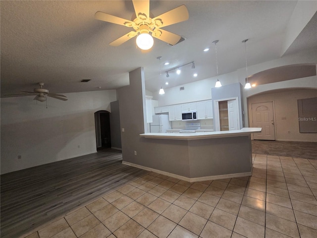 kitchen with white appliances, kitchen peninsula, hanging light fixtures, white cabinetry, and ceiling fan