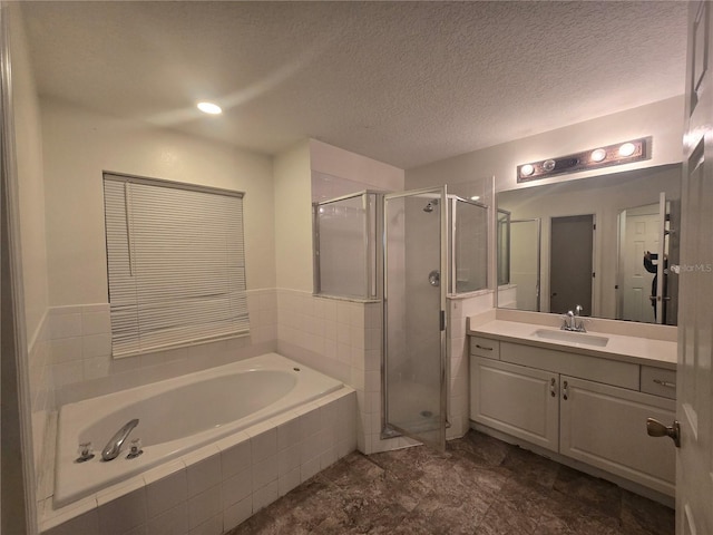 bathroom with independent shower and bath, a textured ceiling, and vanity