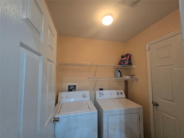 laundry area with a textured ceiling and washing machine and clothes dryer