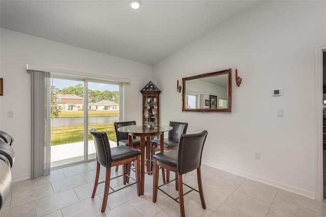 tiled dining room featuring a water view and vaulted ceiling