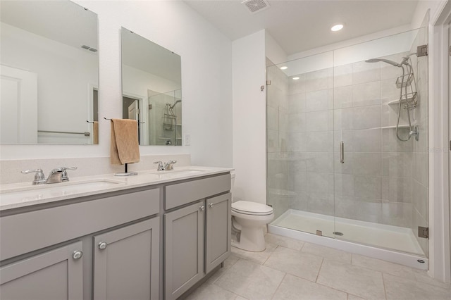 bathroom featuring tile patterned floors, a shower with door, vanity, and toilet