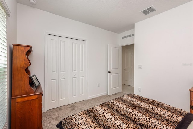 carpeted bedroom with a textured ceiling and a closet