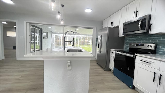 kitchen with white cabinetry, sink, stainless steel appliances, light hardwood / wood-style flooring, and a center island with sink