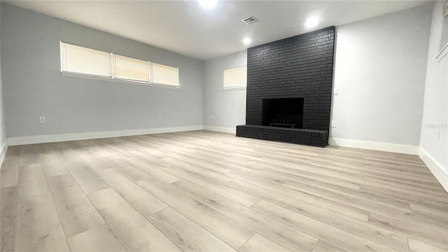 unfurnished living room featuring a fireplace and light hardwood / wood-style floors