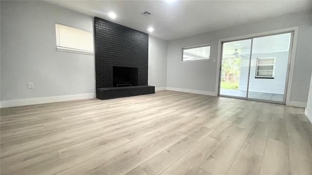 unfurnished living room with ceiling fan, light hardwood / wood-style flooring, and a brick fireplace