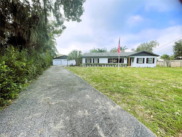 single story home featuring a garage, an outbuilding, and a front yard