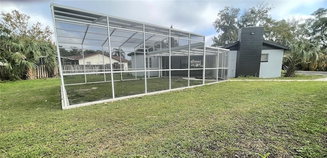 exterior space with glass enclosure and a yard