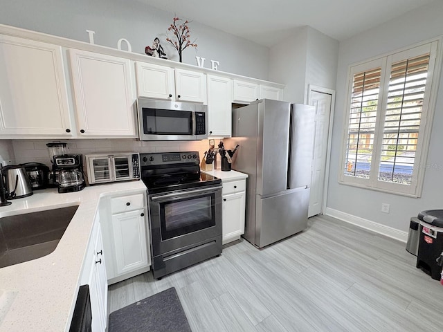 kitchen with decorative backsplash, sink, white cabinetry, and stainless steel appliances