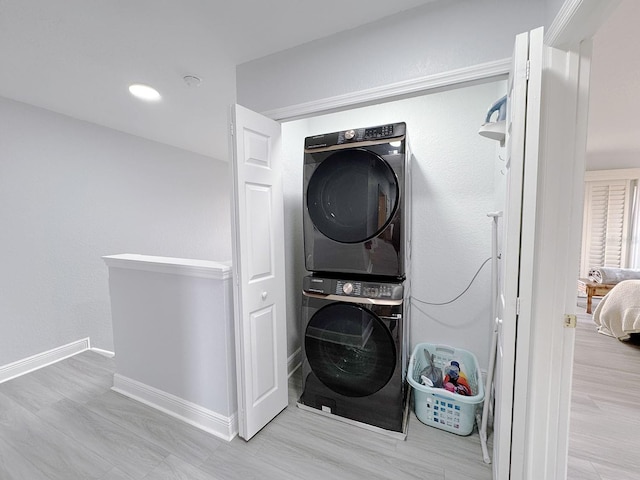 laundry room with stacked washer / drying machine and light wood-type flooring