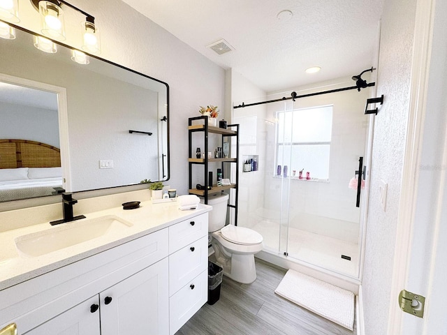 bathroom featuring hardwood / wood-style floors, vanity, toilet, a textured ceiling, and walk in shower