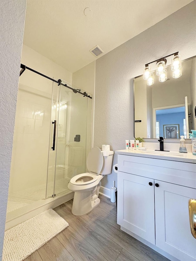 bathroom with toilet, vanity, wood-type flooring, and walk in shower